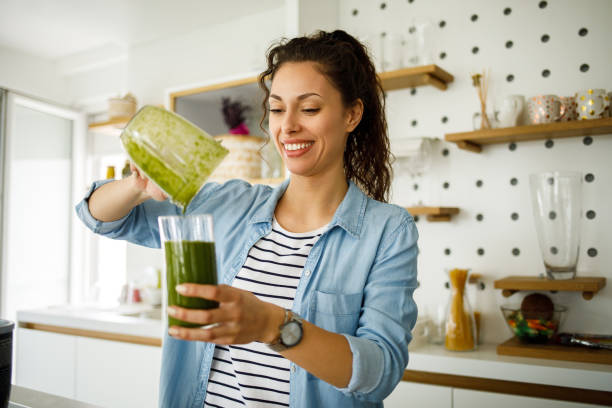 woman preparing a green smoothie for breakfast